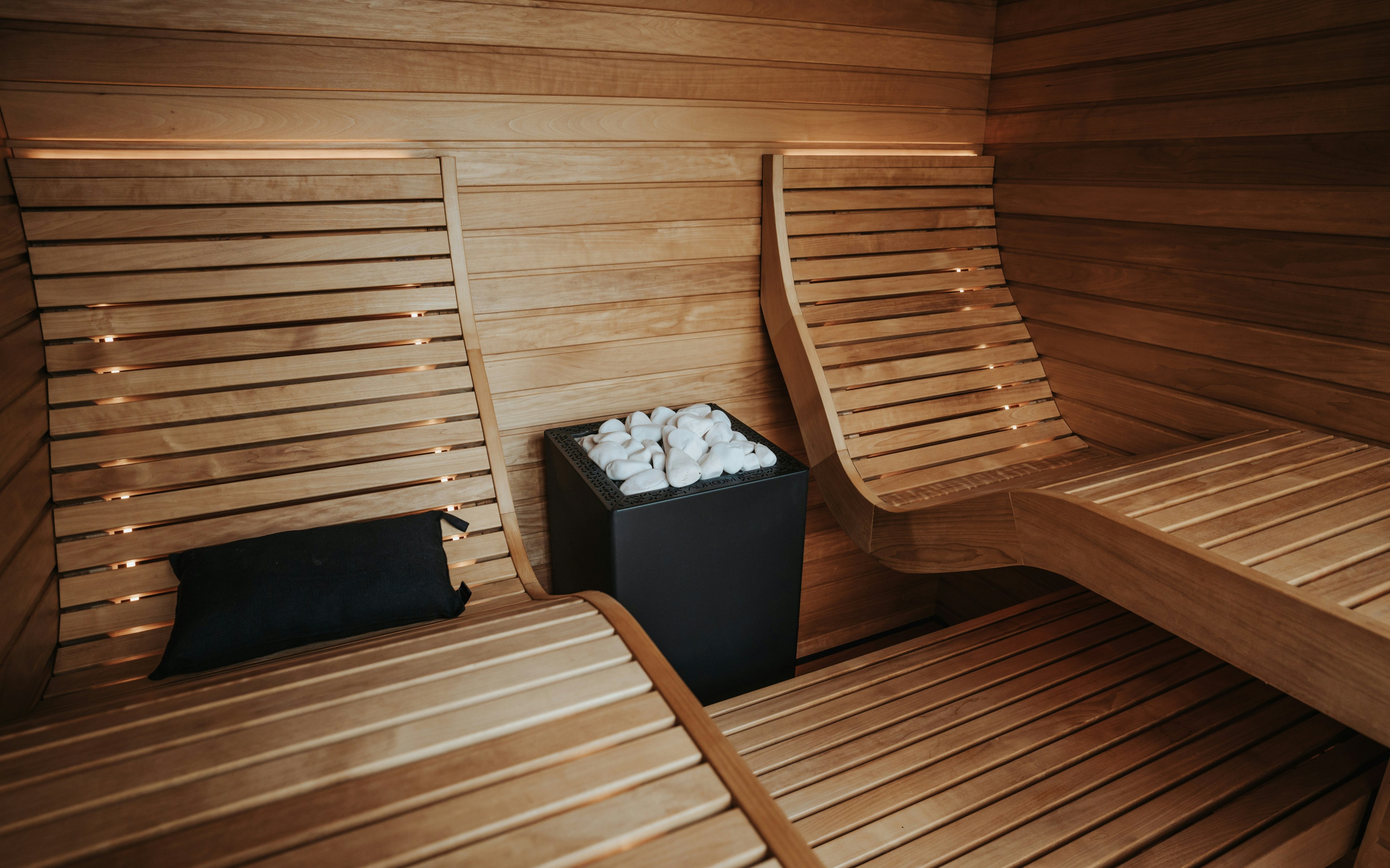 Moderna sauna interna in legno con panche e stufa, progettata per il relax e il ringiovanimento della pelle