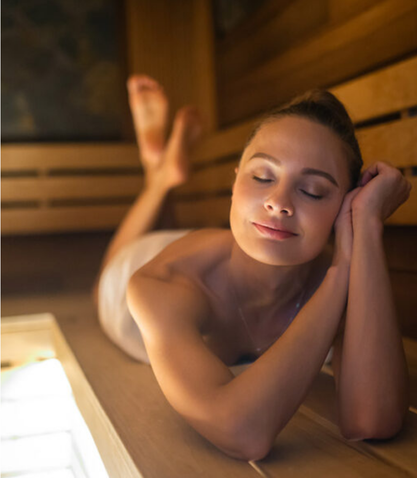 Una donna si riposa sdraiata su una panca della sauna