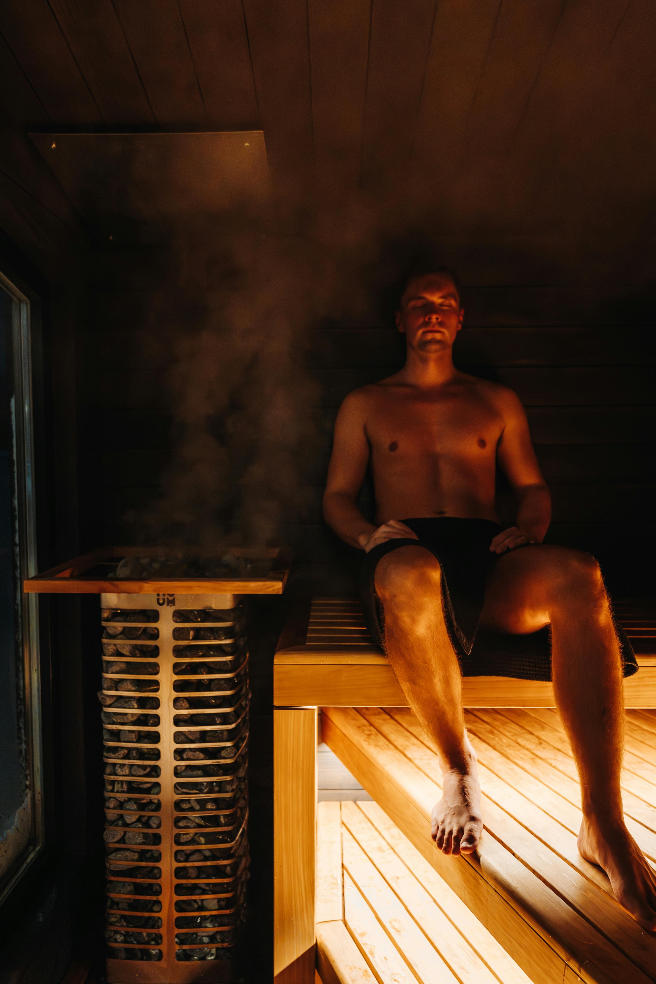 Un uomo è seduto in una sauna vicino a una stufa fumante