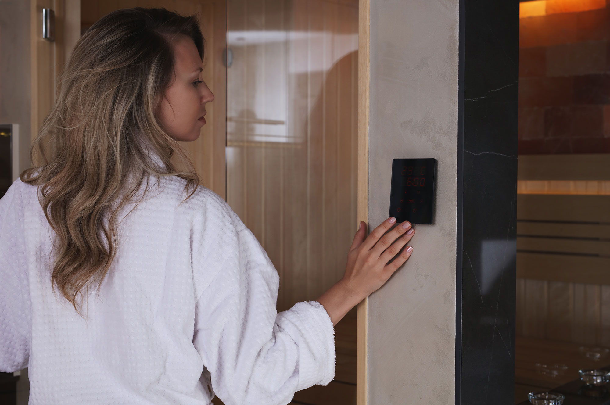 una donna regola il pannello di controllo della sauna