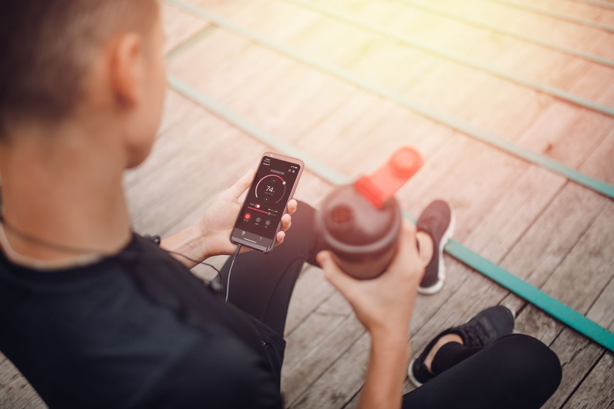 atleta che tiene in mano una bottiglia d'acqua e un telefono