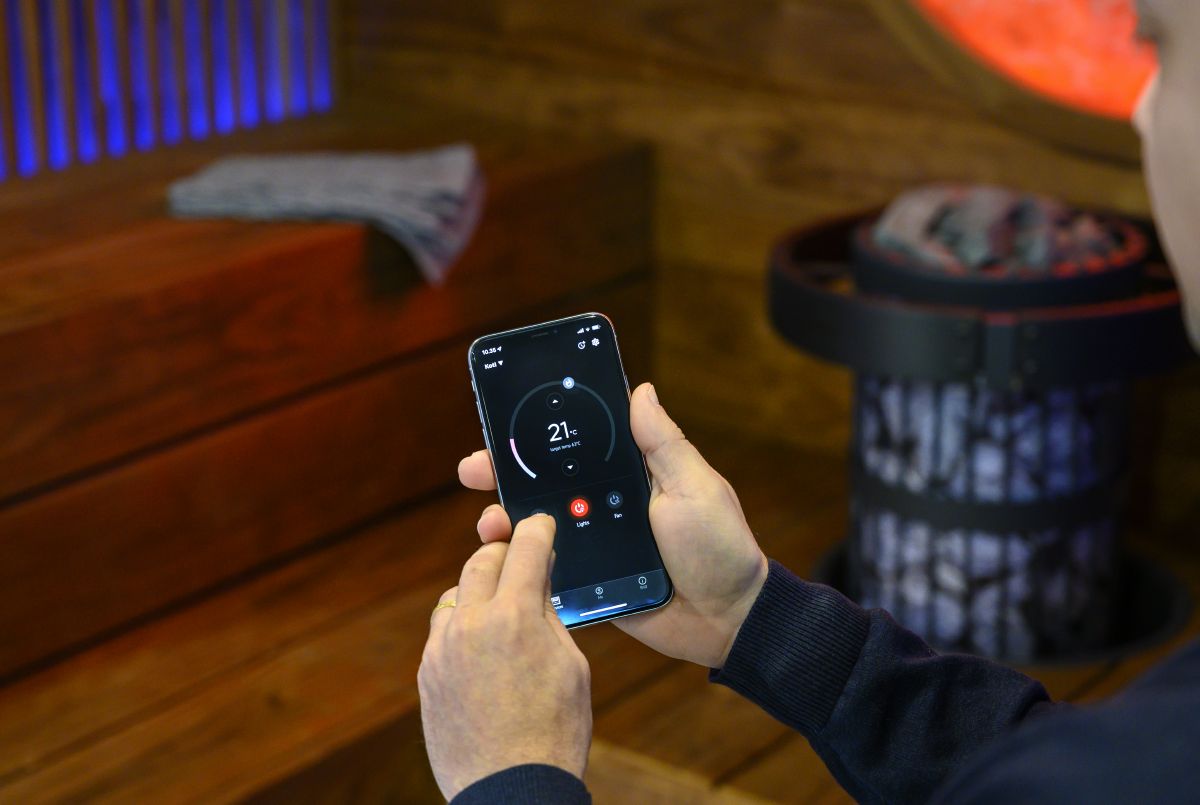 persona che controlla l'attrezzatura della sauna con l'app mobile MyHarvia