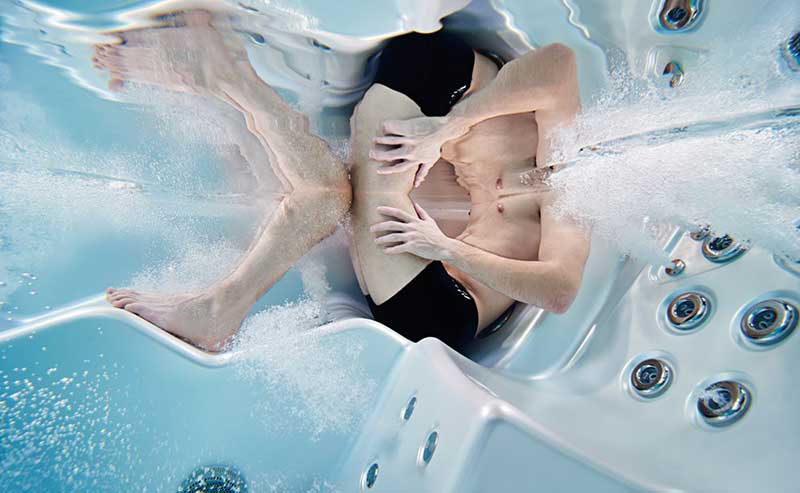 Donna che si rilassa su una sdraio ergonomica in una piscina termale USSPA con getti idromassaggio in funzione.