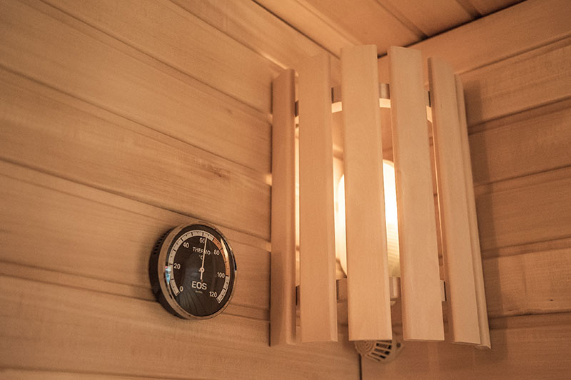 Termometro per sauna EOS e paralume in legno nell'angolo.