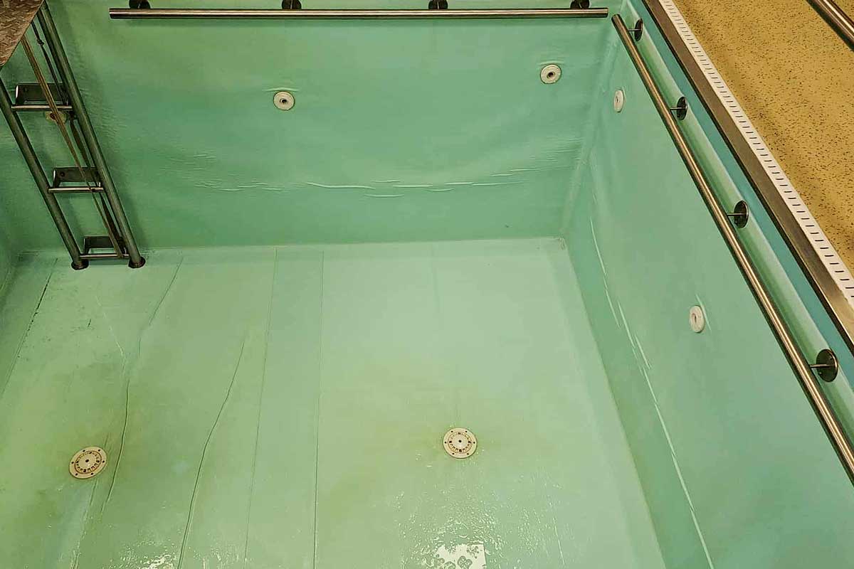 Il fondo della piscina è ricoperto da uno strato di alghe verdi, l'acqua è torbida e dà l'impressione di un ambiente trascurato e sporco.
