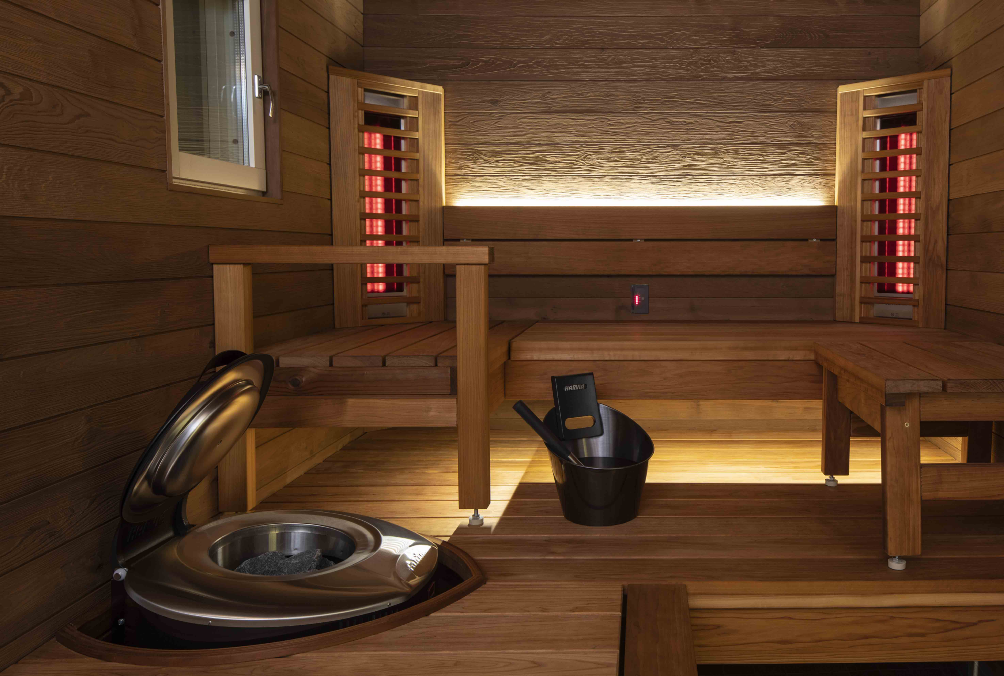 Interno della sauna a infrarossi con panche in legno, elementi riscaldanti e stufa per il relax e il benessere